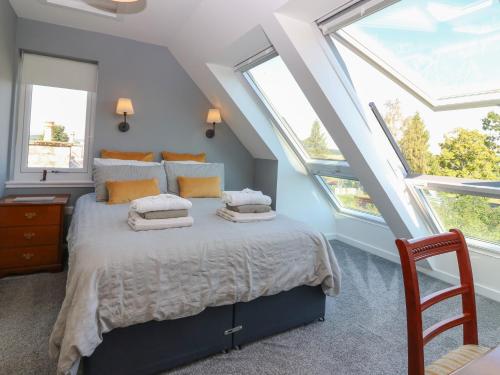una camera da letto con un letto grande con due finestre di Berg Cottage a Ballindalloch