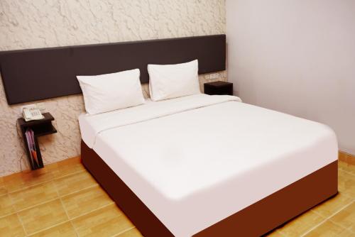 a bedroom with a large bed with white sheets and pillows at Grande Hotel Lampung Powered by Archipelago in Lampung