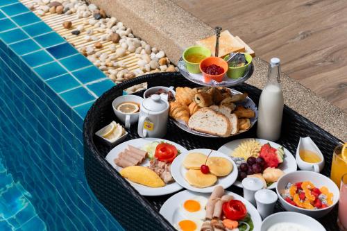 un vassoio con prodotti per la colazione accanto alla piscina di Rawayana West Villas & Kids Park a Rawai Beach