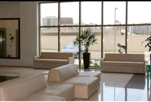 a living room with white furniture and a large window at Via Première - Suíte - Riocentro - Barra Olímpica - Vista Panorâmica in Rio de Janeiro