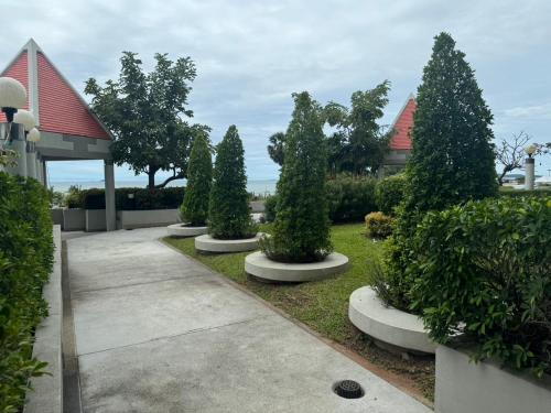 a row of trees in a garden with a gazebo at Jomtien Beachfront Apartment in Jomtien Beach