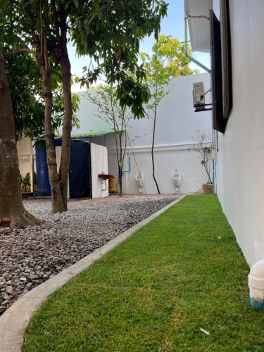 a side yard with grass and trees next to a building at Por Chey Guesthouse in Battambang