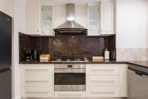 a kitchen with white cabinets and a stove top oven at Diamonds By The Dock Spacious,central Quality in Fremantle