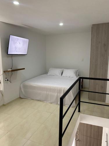 a bedroom with a bed and a flat screen tv at Apartamento en Las Mercedes tipo Loft in Palmira