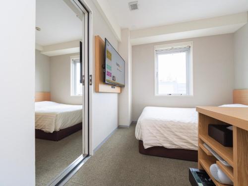 a hotel room with two beds and a mirror at Super Hotel Ueno-Okachimachi in Tokyo