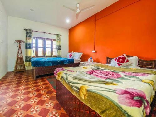 a room with two beds and an orange wall at Hotel Tiger's Den - Peace Home, Family in Sauraha