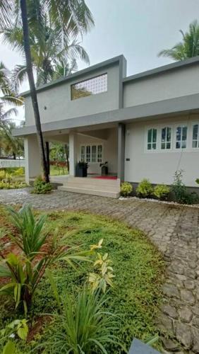 a large white house with palm trees in front of it at Villa Avni, a beach side family retreat, Homestay in Nīleshwar