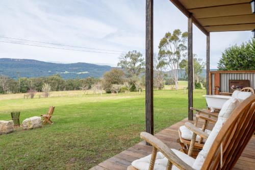 a porch with chairs and a bath tub on it at 'Casuarina' - Picturesque Kangaroo Valley Cottage in Kangaroo Valley