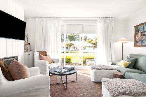 a living room with white furniture and a large window at The Waratah Cottage in Robertson