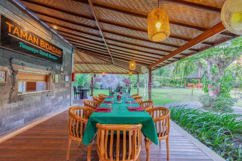 a dining room with a green table and chairs at Taman Bidadari Eco Wellness in Pemuteran