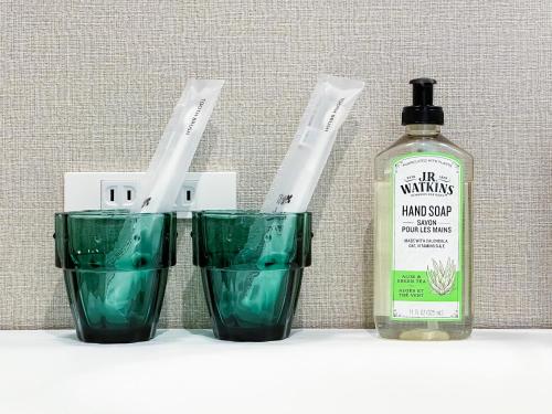 three green glasses sitting next to a bottle of alcohol at Saboten in Sesoko