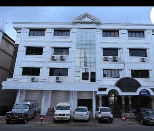 a white building with cars parked in front of it at Hotel Swadesh Heritage in Udupi