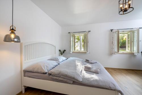 a white bedroom with a large bed with two windows at Apartmány Pernek in Horní Planá
