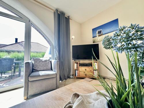 a living room with a chair and a large window at Haus Emmi - Hooksiel in Wangerland