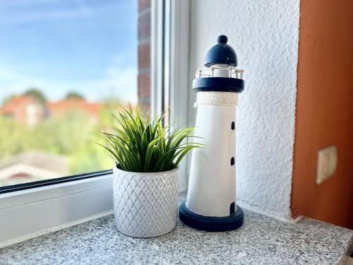 a lighthouse sitting on a window sill next to a plant at Haus Emmi - Hooksiel in Wangerland