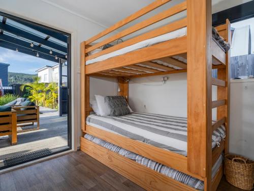 Un dormitorio con una litera y un balcón. en Sunny Hideaway - Whangamata Holiday Home, en Whangamata