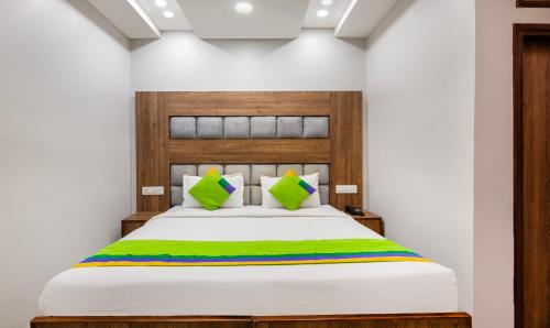 a bedroom with a white bed with a green blanket at Treebo JD Residency Mohali in Chandīgarh