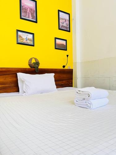 a bedroom with a white bed with a yellow wall at Por Chey Guesthouse in Battambang