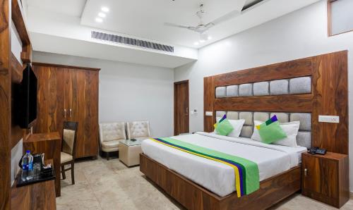a bedroom with a large bed and a chair at Treebo JD Residency Mohali in Chandīgarh