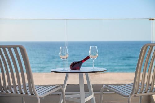 ArtCotel Luxury Villa في مدينة ريثيمنو: طاولة مع كأسين من النبيذ وكرسيين