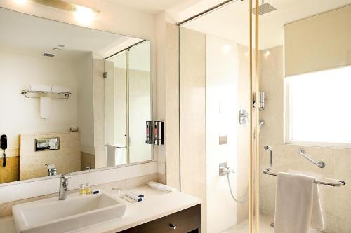 Un baño con lavabo y ducha con espejo. en Inde Hotel Vista Woods Huda City Centre, Gurgaon, en Gurgaon