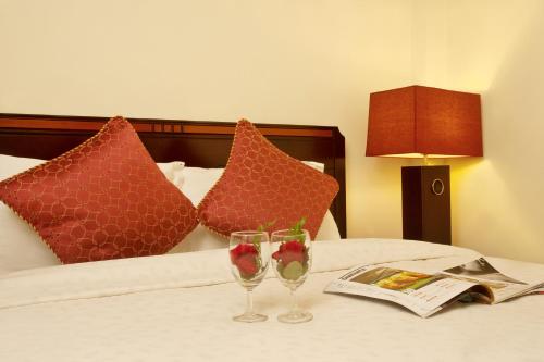 a bed with two wine glasses and a newspaper at Lien An Sai Gon Hotel in Ho Chi Minh City
