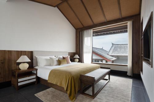 a bedroom with a large bed and a large window at La Maison Hotel - Lijiang in Lijiang