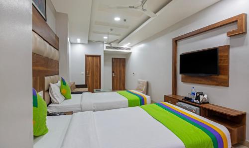 a bedroom with two beds and a flat screen tv at Treebo JD Residency Mohali in Chandīgarh