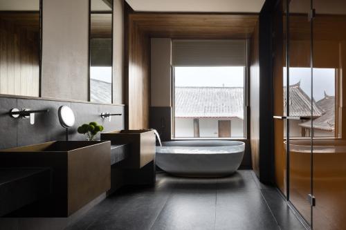 a bathroom with a tub and a sink and a window at La Maison Hotel - Lijiang in Lijiang