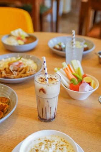 a wooden table with plates of food and a drink at Bloom Hotel Katra in Katra