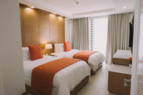 a hotel room with two beds and a television at PonteFino Hotel in Batangas City