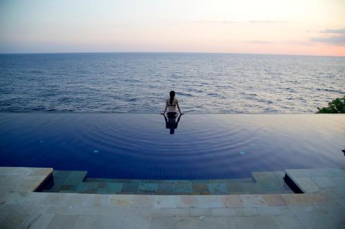 a person sitting in the water in the ocean at Villa Infinite Horizon in Amed