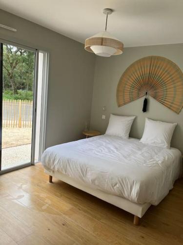 une chambre avec un grand lit et une grande fenêtre dans l'établissement Villa estagnots bourdaine lac hossegor, à Seignosse