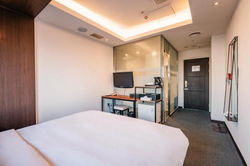 Un dormitorio con una cama y un escritorio con televisión. en The Riverside Hotel, en Seúl