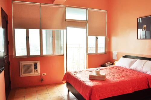 a bedroom with orange walls and a bed with a red bedspread at GV Tower Hotel in Cebu City