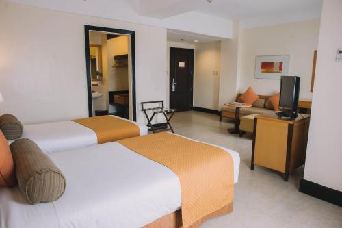 a hotel room with two beds and a television at PonteFino Hotel in Batangas City