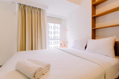 a bedroom with a large white bed with a window at Modern Look and Comfy Studio Tokyo Riverside PIK 2 Apartment By Travelio in Rawalembang