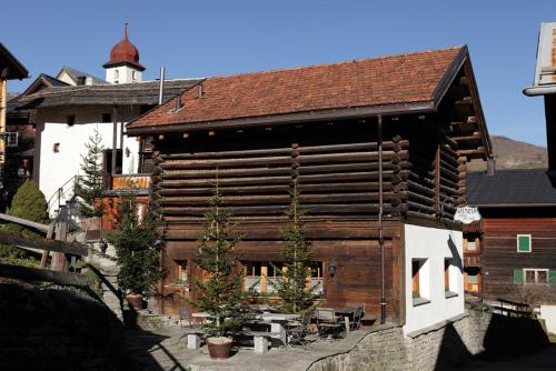a large wooden building with a tower in the background at Chalets Casa da Luzi in Surcasti