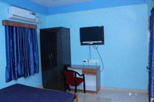 a bedroom with a bed and a desk with a television at SEA SUN PARADISE in Port Blair