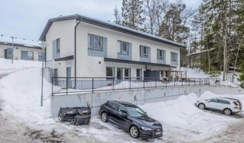 two cars parked in front of a house in the snow at Cozy and modern apartment in Luoma