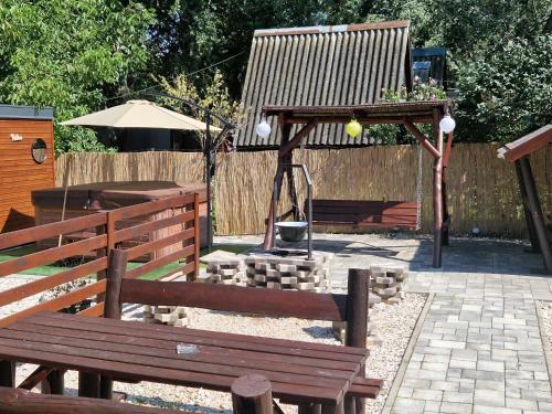 two wooden benches in a garden with a fire place at Sarudi Wellness Apartman in Sarud