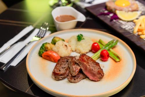 a plate of food with meat and vegetables on a table at Mintra Hotel in Vientiane