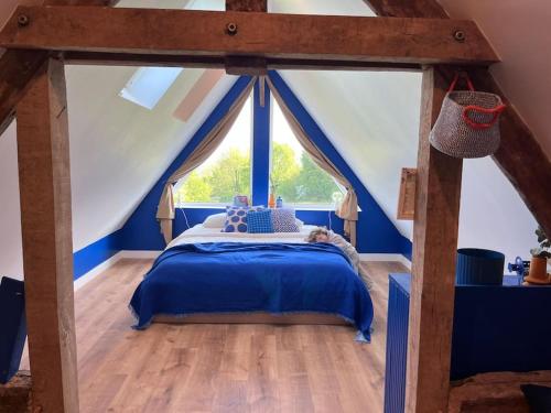 - une chambre avec un lit bleu et une grande fenêtre dans l'établissement Magnifique maison au coeur de la campagne normande, à La Chapelle-Haute-Grue