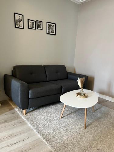 a living room with a black couch and a white table at Maison de ville - 8 couchages in Saint-Pierre-le-Moûtier