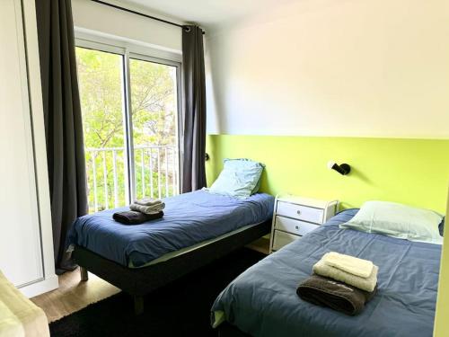 deux lits dans une chambre avec une fenêtre dans l'établissement Le Korrigane La Baule, au Pouliguen