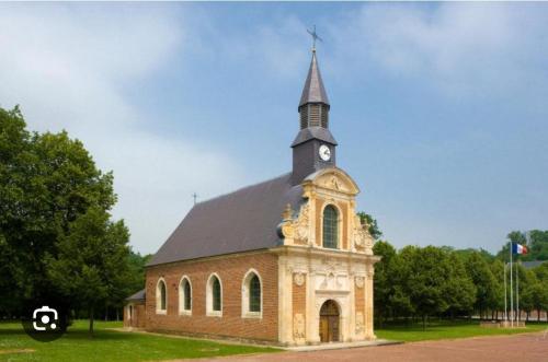 a church with a steeple with a clock on it at Entre les places, spacieux avec Parking Gratuit in Arras