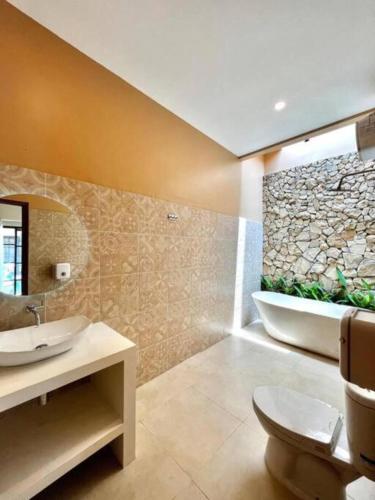 a bathroom with a toilet and a sink and a tub at Sampai Villa Sahara in Yogyakarta