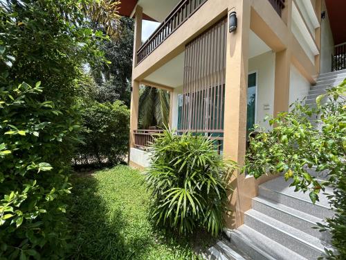 a house with stairs and plants in the yard at Mina House in Baan Tai