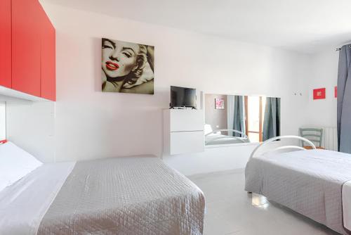 a white bedroom with a bed and a painting of a woman at On the Beach in Tortoreto Lido