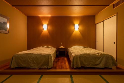 a bedroom with two beds and two lights on the wall at Kinugawa Hotel Mikazuki in Nikko